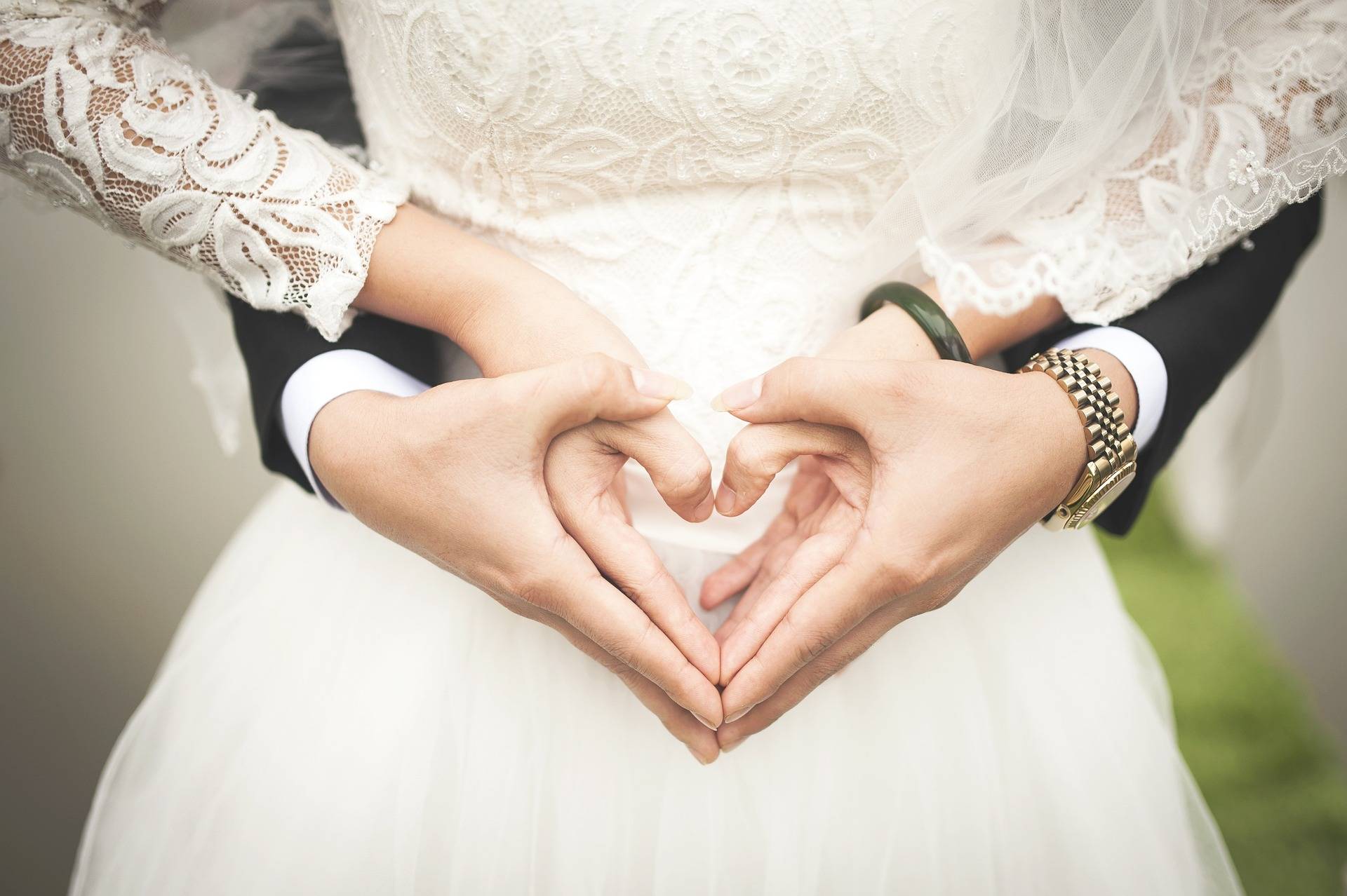 Detailaufnahme von einem Brautpaar, das seine Hände zu einem Herz formt